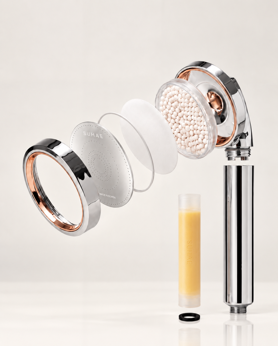 Exploded SUHAE Radiance showerhead showing its spray plate, filtration media and vitamin C cartridge